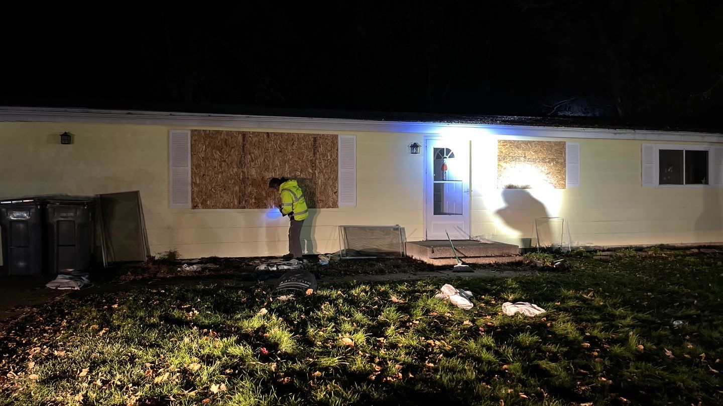 a man boarding up windows of a house
